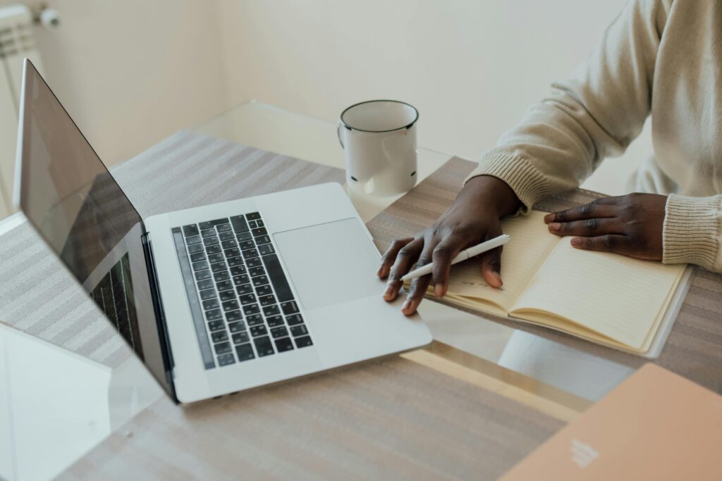 A minimalist workspace featuring a laptop, journal, and pen, perfect for remote work.